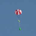 White and red rocketry and drone parachute over rocket and descending after ejection