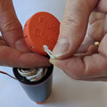 Demonstration of threading a parachute shock cord through the cap of a drone parachute launcher