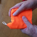 Demonstration of wrapping a parachute liner around a parachute while leaving the end of the shock cord out