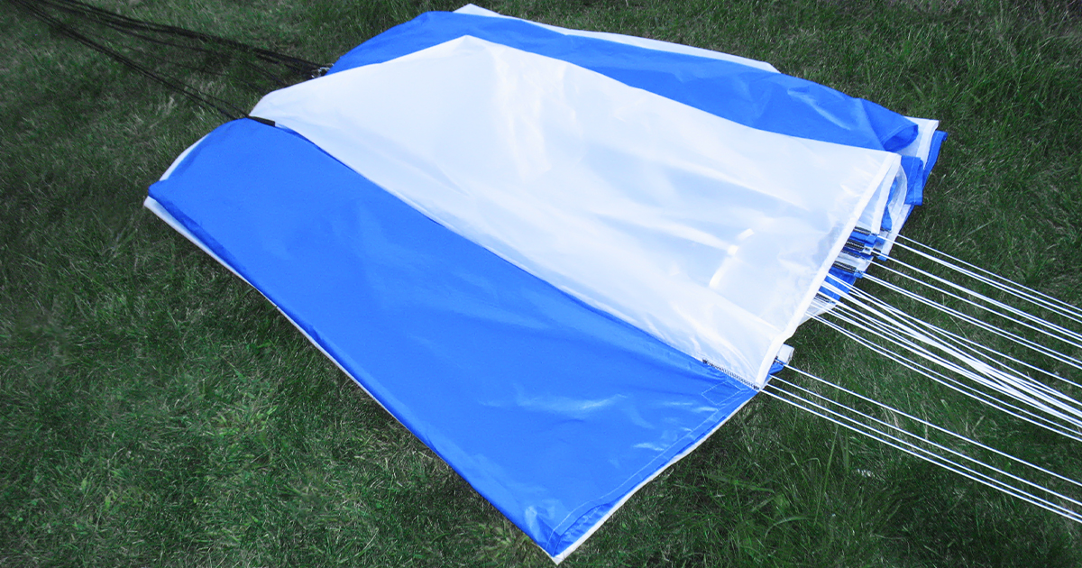 Side view of parachute laid on field with shroud lines extended