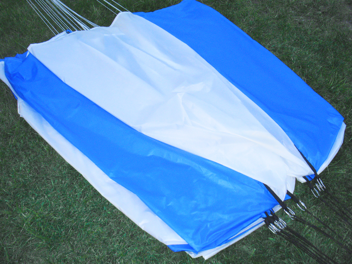 Side close-up view of parachute laid on field with load harness connections on the shroud lines